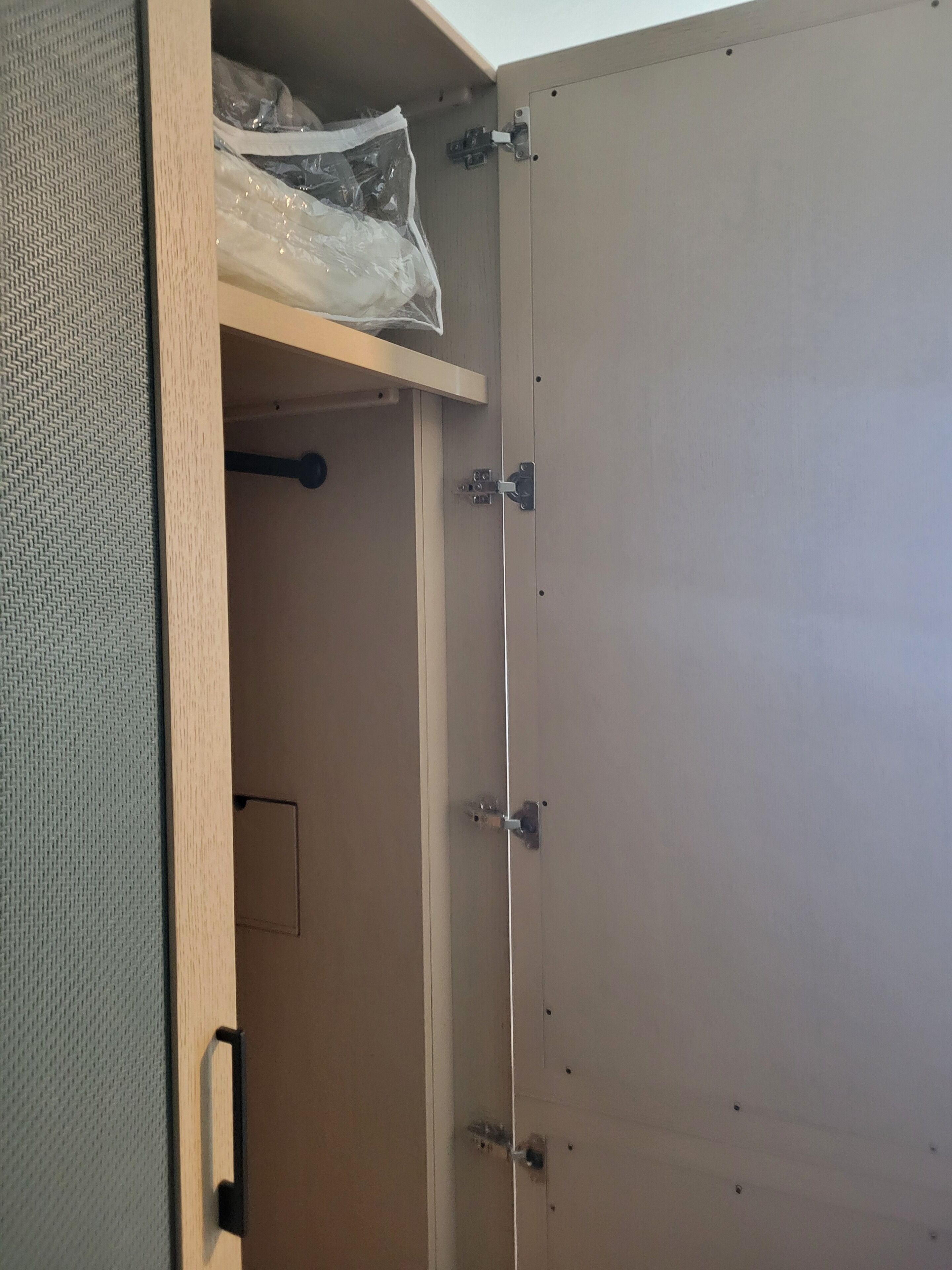 Een gedeeltelijk open kast met een kledingstang en een klein opbergdoosje.