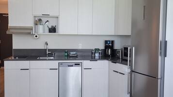 Una cucina moderna con mobili bianchi, elettrodomestici in acciaio inossidabile e lavastoviglie integrata.