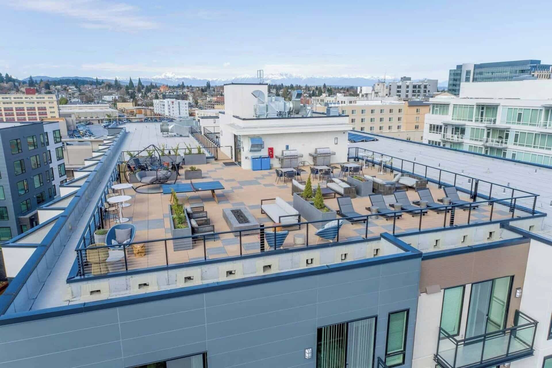 A rooftop terrace with outdoor seating, a pool, and a view of the cityscape.