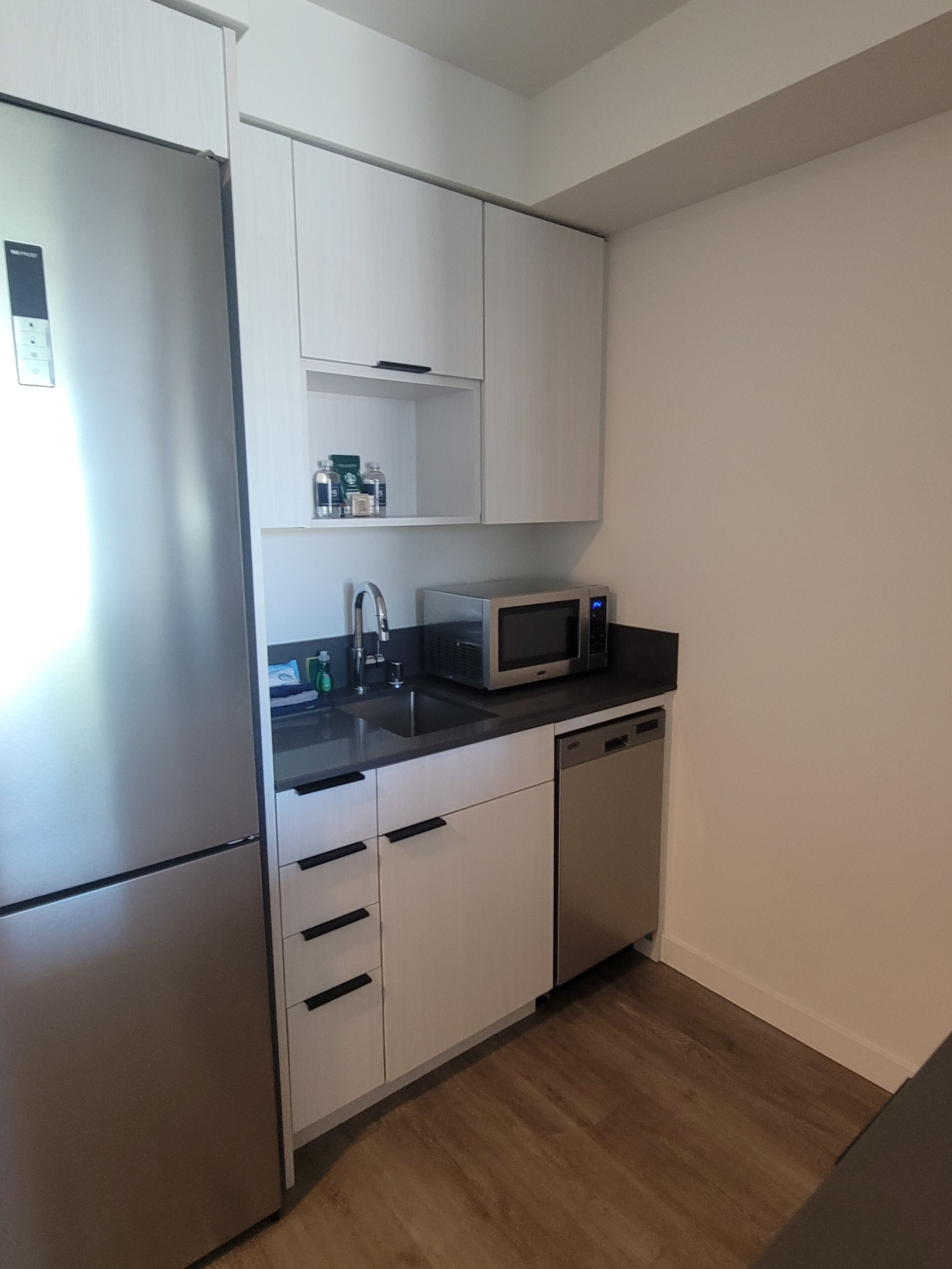 A compact kitchen with a refrigerator, microwave, sink, and dishwasher.