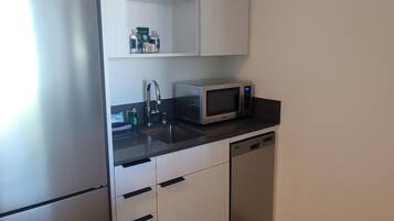 A compact kitchen with a refrigerator, microwave, sink, and dishwasher.