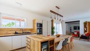 Een moderne keuken met een houten keukeneiland, ingebouwde apparatuur en een eethoek met stoelen en een tafel.