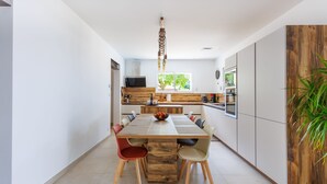 Een moderne keuken met een houten eettafel, stoelen en een hanglamp.