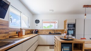 Een moderne keuken met een houten aanrechtblad, ingebouwde apparatuur en een groot raam.