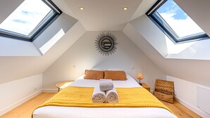 Un dormitorio con tragaluces, una cama con manta amarilla y un adorno de pared con forma de sol.
