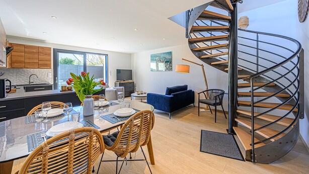 Una cocina moderna con comedor, un sofá azul y una escalera en espiral.