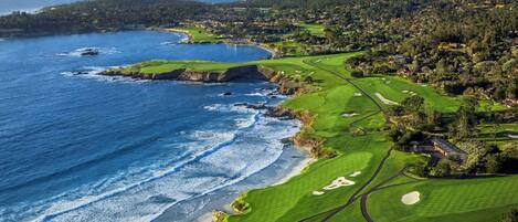 A coastal golf course with a view of the ocean and residential areas.