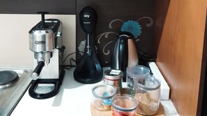 A kitchen area with a coffee maker, a kettle, and various containers on the counter.