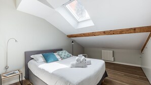 A modern bedroom with a skylight, a bed with white linens, and a wooden floor. - Le Jarente - Appt pour 2 centre de Lyon (Lyon)