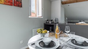 A modern kitchen with a dining area, featuring a large window, a bowl of fruit, and a bottle of wine on the table. - Le Jarente - Appt pour 2 centre de Lyon (Lyon)