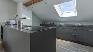 A modern kitchen with a central island, grey cabinetry, a skylight, and a wooden ceiling beam. - Le Jarente - Appt pour 2 centre de Lyon (Lyon)