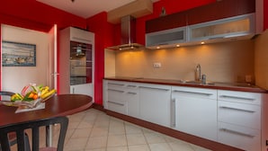 Uma cozinha moderna com armários brancos, bancada de madeira e uma parede em vermelho.