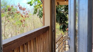 A covered outdoor corridor with a wooden railing, leading to a door.