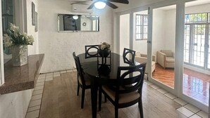 A dining area with a round table and chairs, a ceiling fan, and a view through glass doors to an outdoor patio. - Acogedora casa dentro de fraccionamiento a orilla de la playa (Mazatlán)