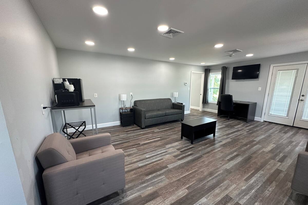 A modern living room with a grey sofa, a black coffee table, and a grey armchair.