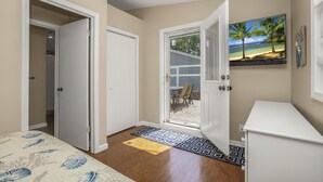 A bedroom with a bed, a door leading to a balcony, and a painting of a beach scene. - Beautiful 6 bedroom lake house. Pontoon available for rent (Union)
