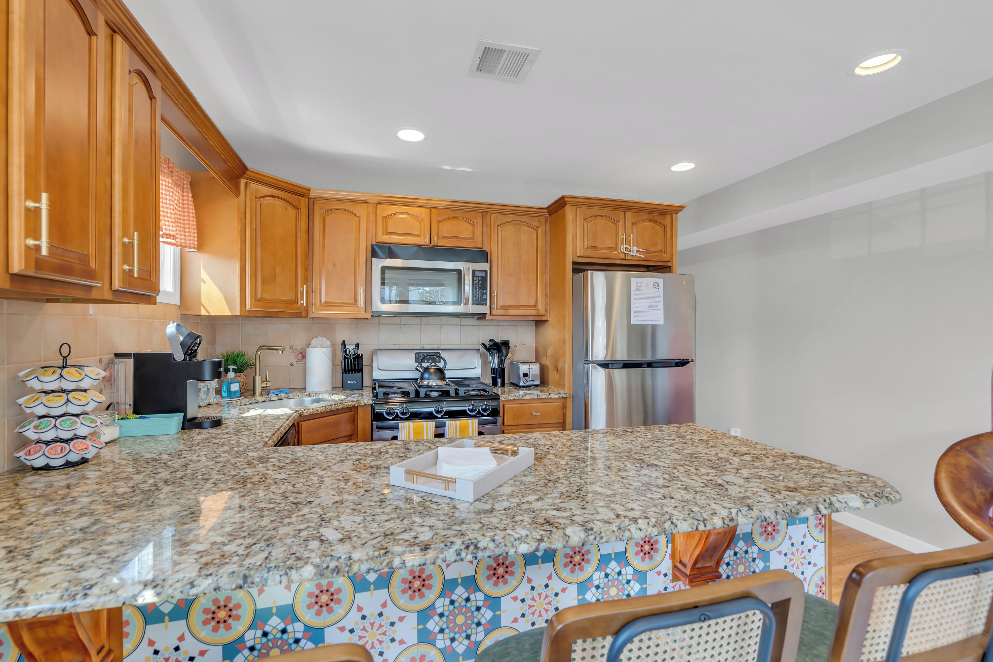A kitchen with wooden cabinets, a stainless steel refrigerator, a microwave, and a stove.