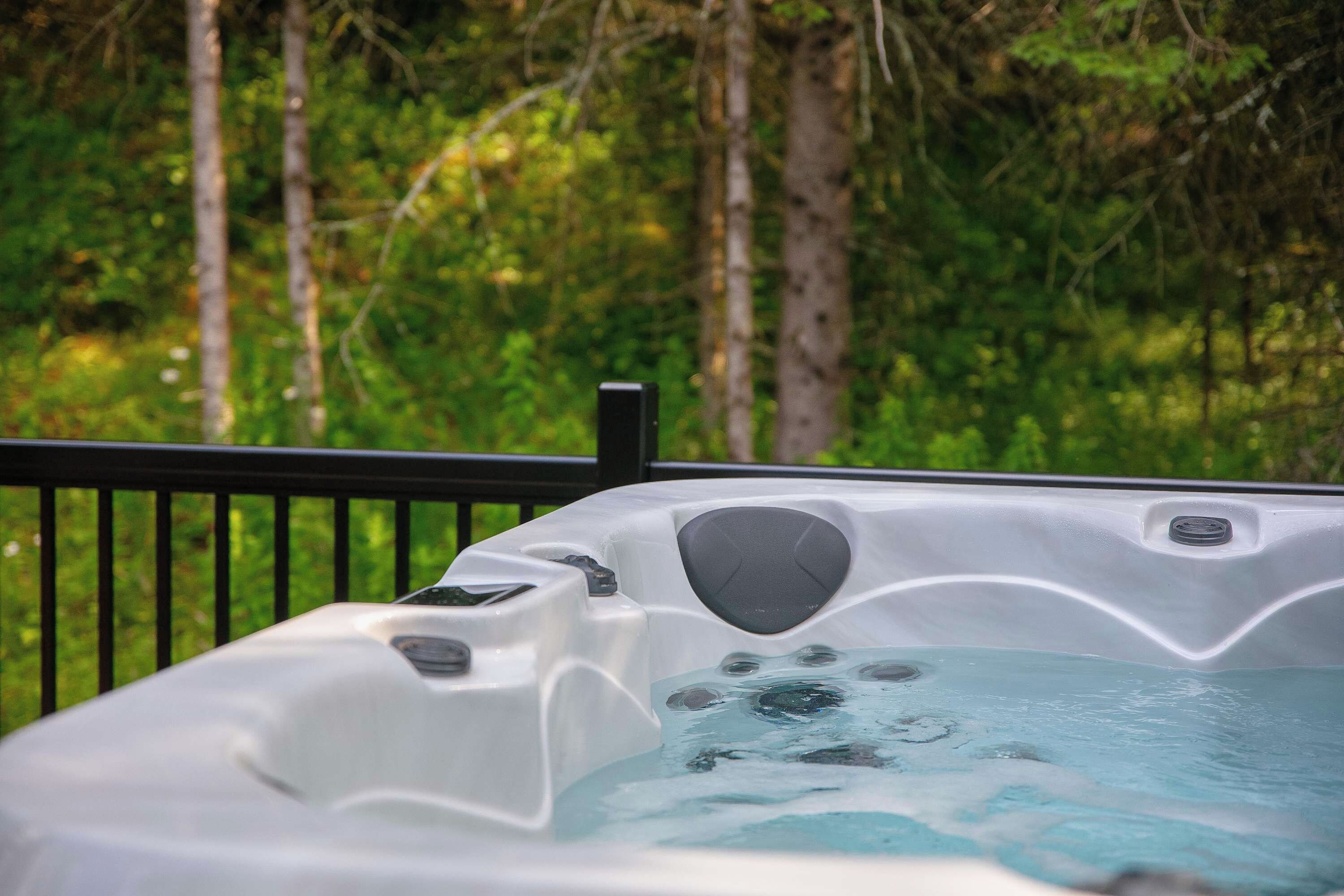 A hot tub with a view of a forested area.