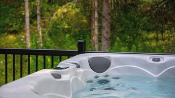 A hot tub with a view of a forested area.