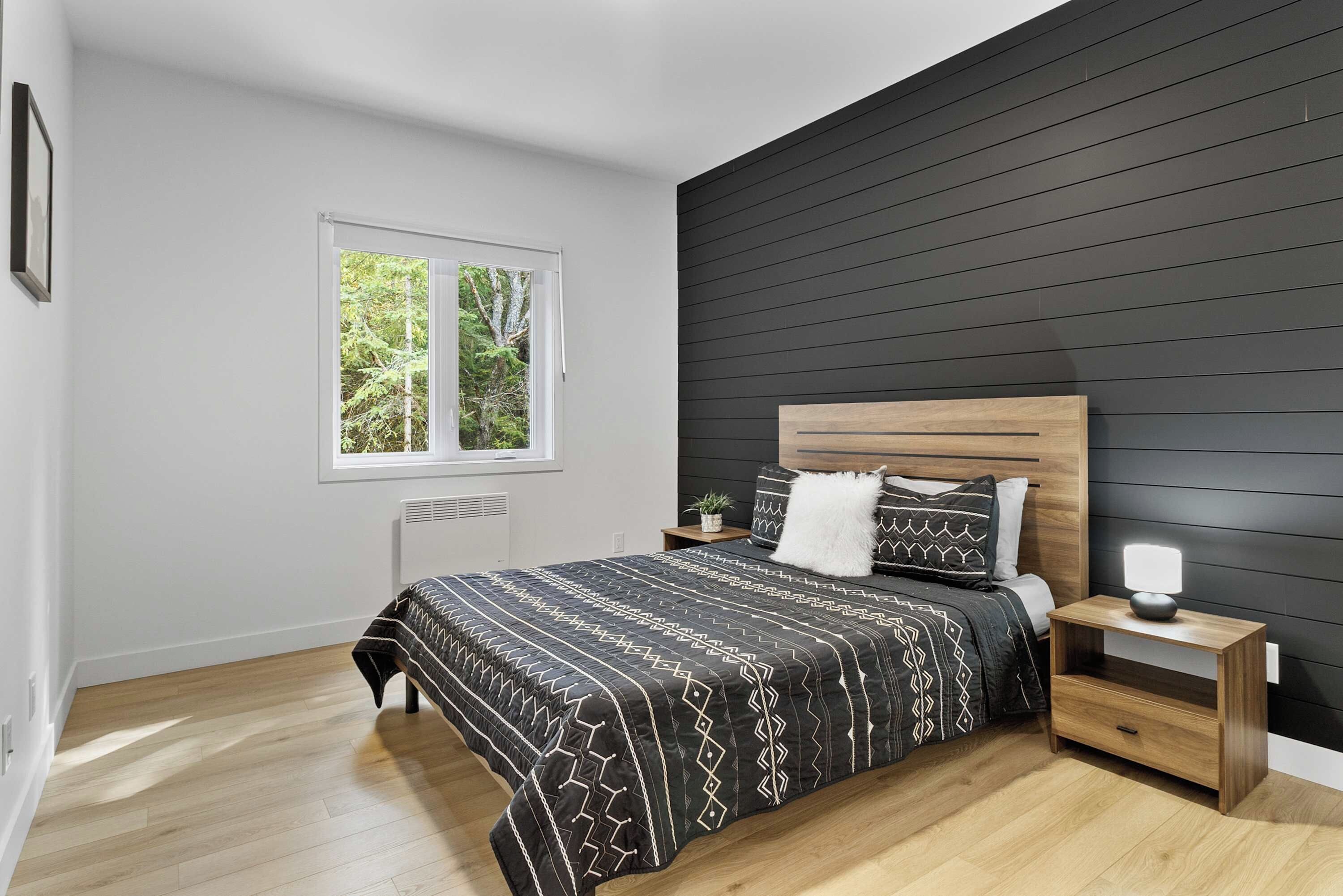 A modern bedroom with a bed, bedside table, and a window.
