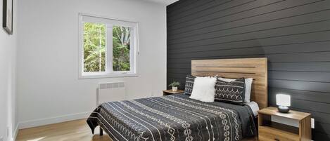 A modern bedroom with a bed, bedside table, and a window.