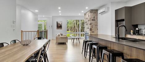 Eine moderne Küche mit einem Holzesstisch, Barhocker und einer Wand mit Steinverkleidung.