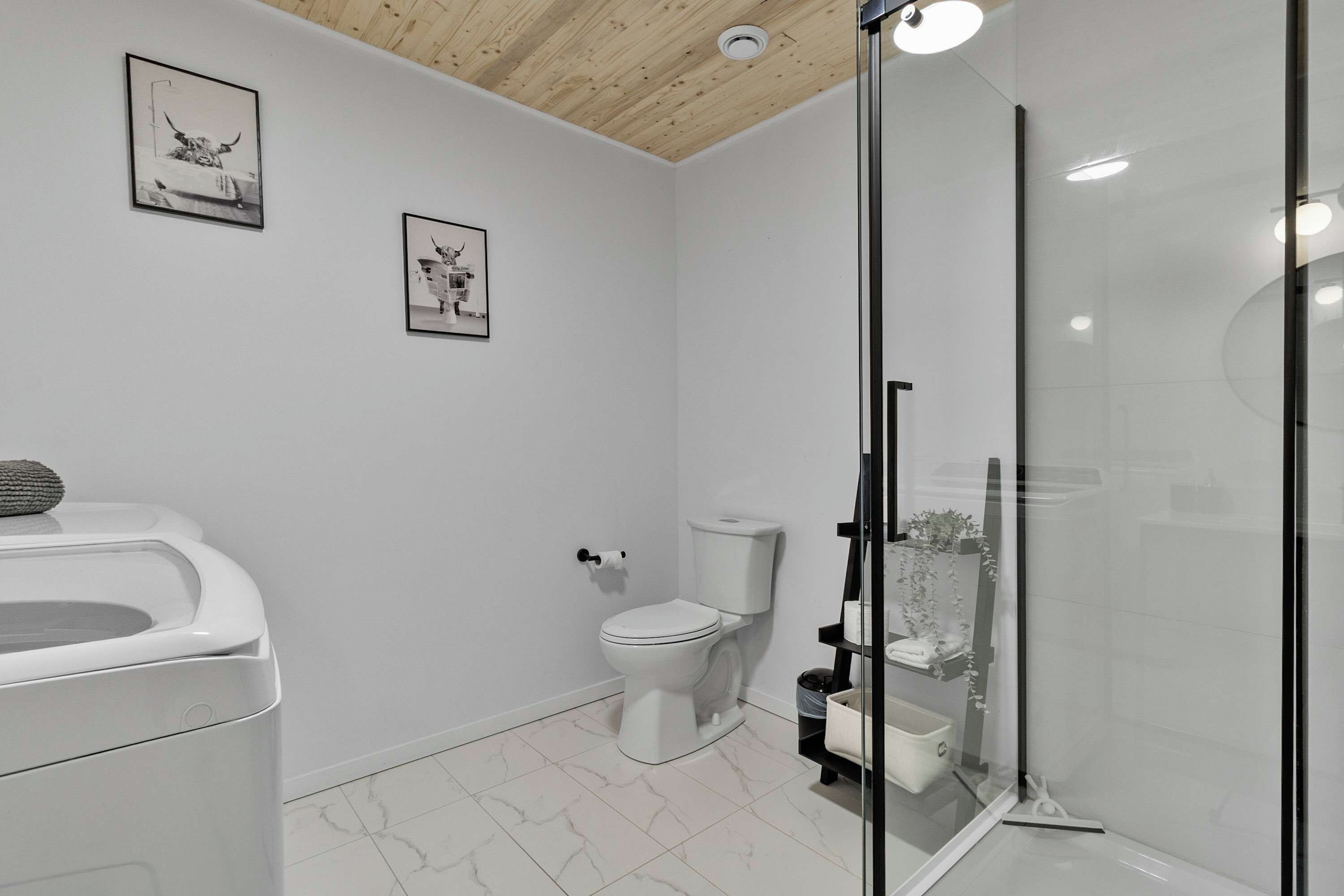 A modern bathroom with a toilet, bidet, and shower. There are two framed pictures on the wall.