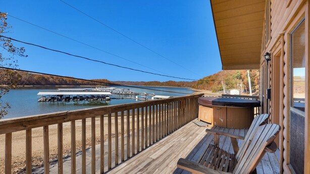 A wooden deck with a hot tub, chairs, and a view of a lake and dock. - Chalet with 2 Bedrooms lakeside to Dale Hollow Lake #17 (Byrdstown)
