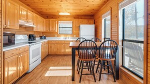A wooden cabin kitchen with a dining table and chairs, wooden cabinets, a stove, and a refrigerator. - Chalet with 2 Bedrooms lakeside to Dale Hollow Lake #17 (Byrdstown)