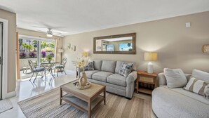 A living room with a grey sofa, a coffee table, a dining table with chairs, and a large mirror on the wall. - Tranquil Siesta Key Retreat ~ Walk to Beach ~ Pool (Siesta Key)