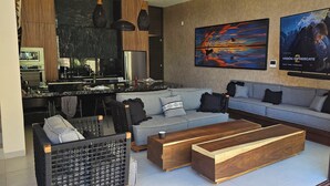 Ein modernes Wohnzimmer mit grauem Sofa, Couchtisch aus Holz und einer Küchenzeile mit einer großen Kochinsel.