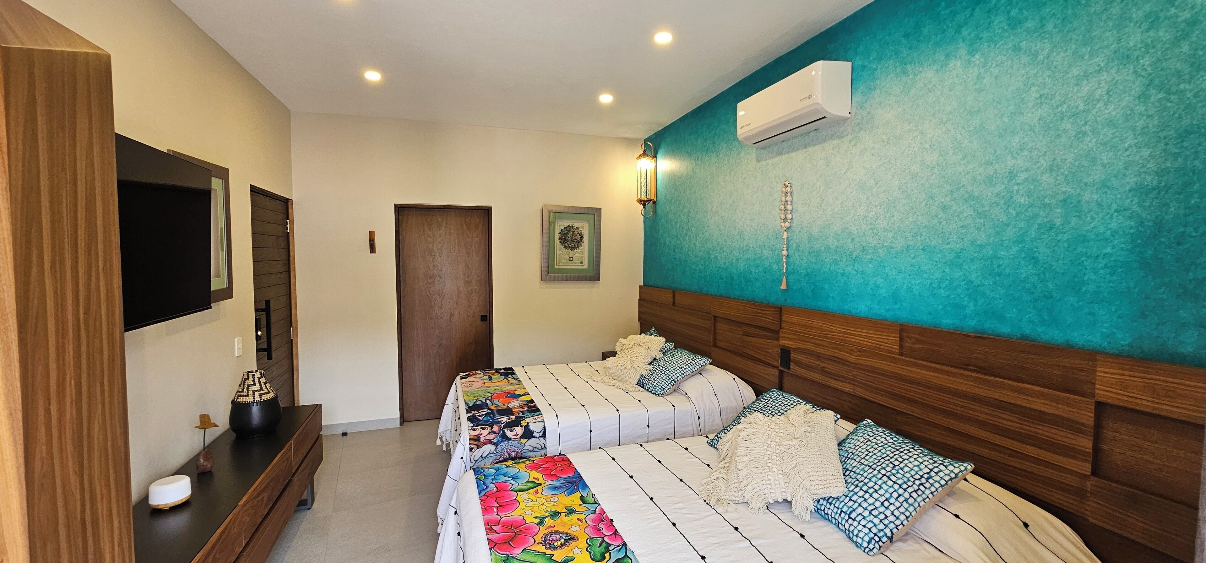 Un dormitorio con dos camas, un televisor, un aparador de madera y un equipo de aire acondicionado.