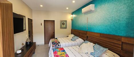 Un dormitorio con dos camas, un televisor, un aparador de madera y un equipo de aire acondicionado.