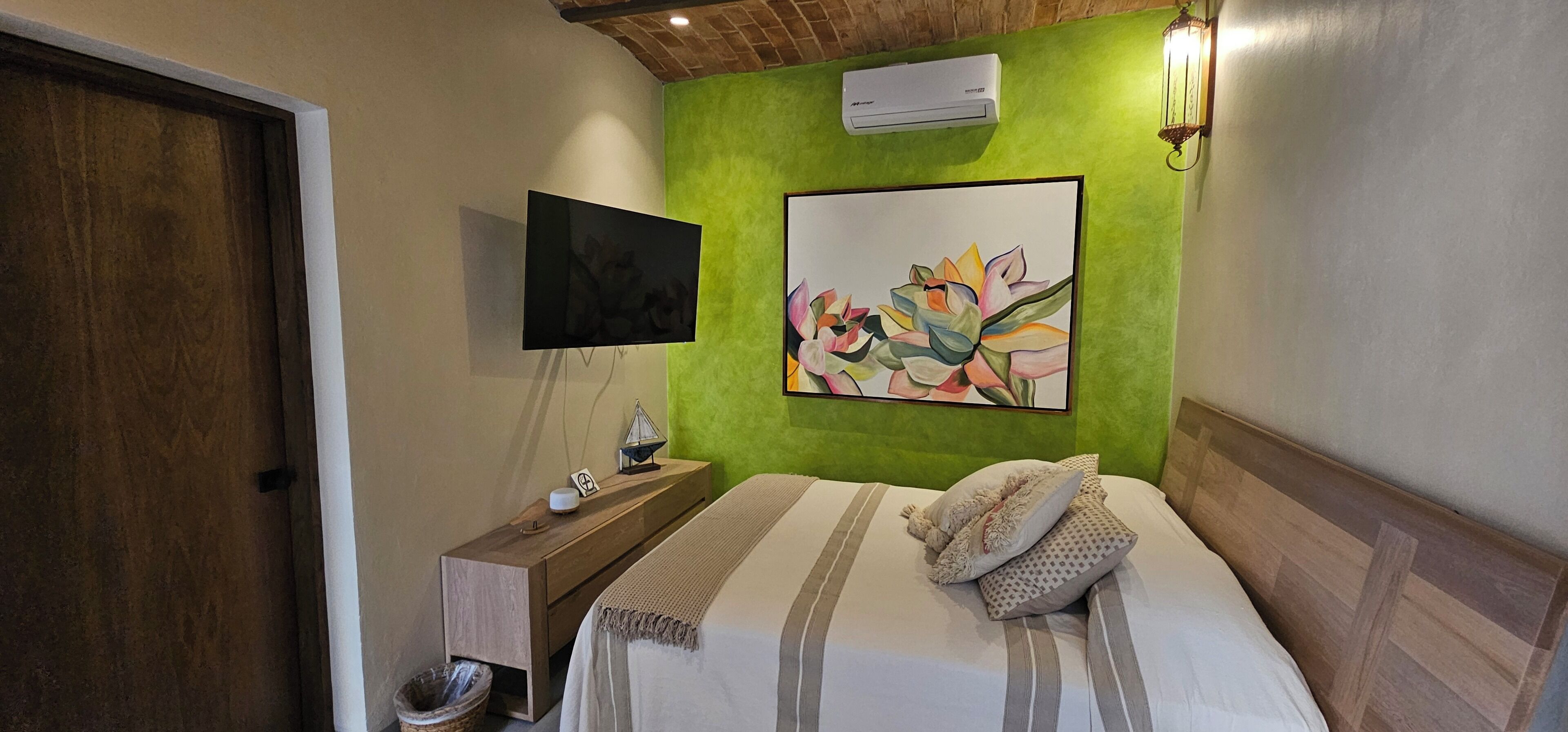A bedroom with a bed, a nightstand, a TV, and a painting on the wall.