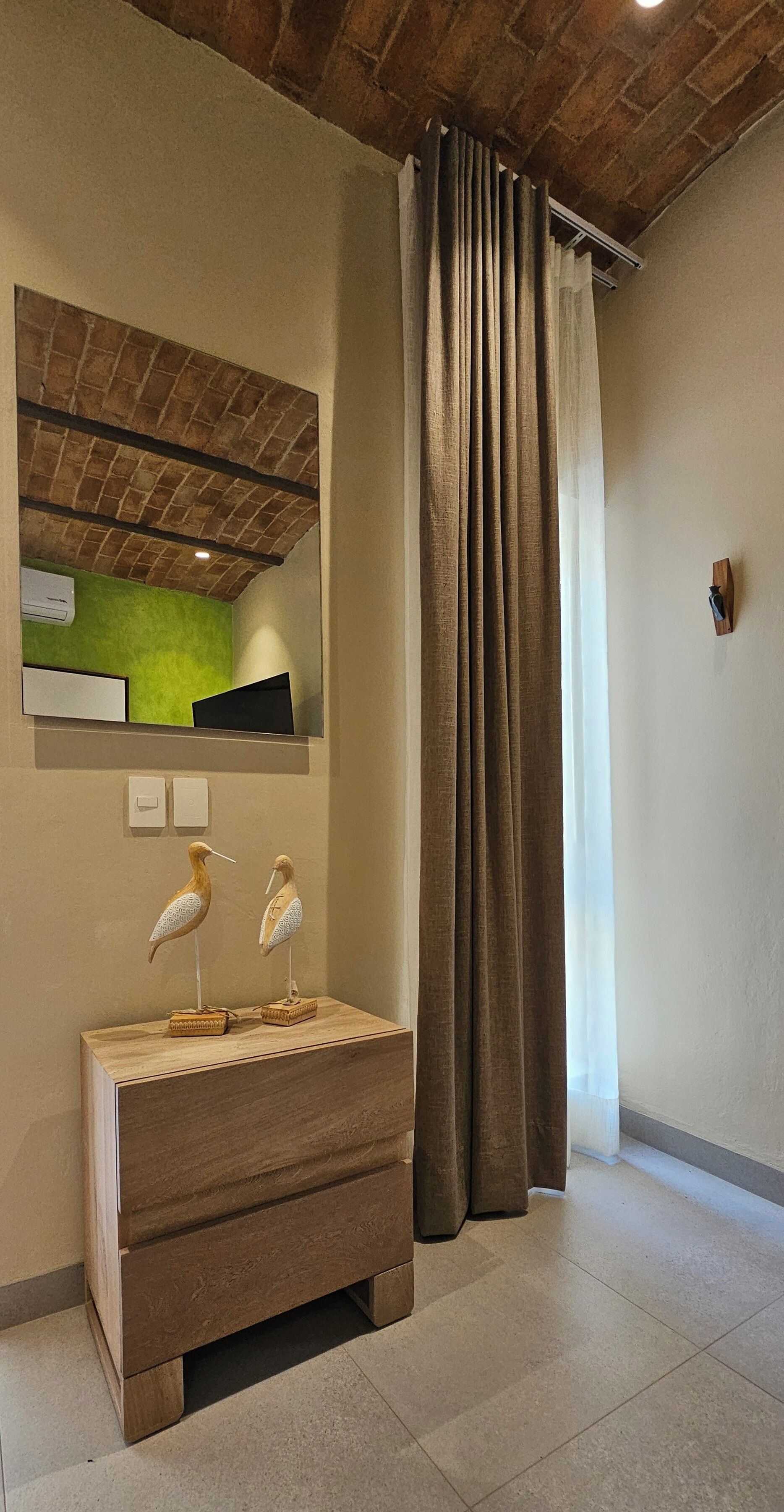 Un baño con tocador de madera, pared verde y espejo arriba.