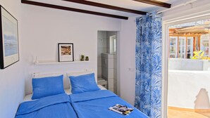 A bedroom with a bed, a shower area, and a view of the outside.