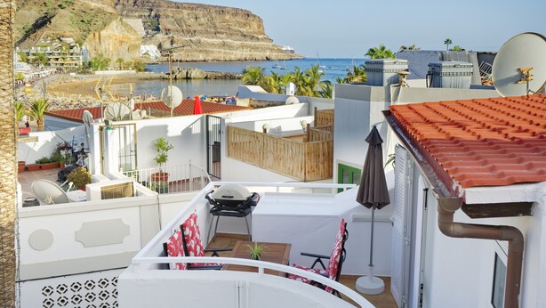 A rooftop terrace with a view of the sea and a cliff.