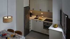 A compact kitchen with white cabinets, a built-in oven, and a dining area with a table and chairs.
