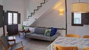 A living room with a sofa, chairs, a table, and a staircase.