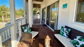 A covered porch with wicker furniture, a lantern, and a sign reading "Welcome to the Beach House." - A Spacious Ocean View Villa, steps away from Punta Cocos bioluminescence beach.  (Holbox)