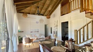 A spacious living area with a wooden ceiling, a dining table set with placemats, and a staircase leading to an upper level. - A Spacious Ocean View Villa, steps away from Punta Cocos bioluminescence beach.  (Holbox)