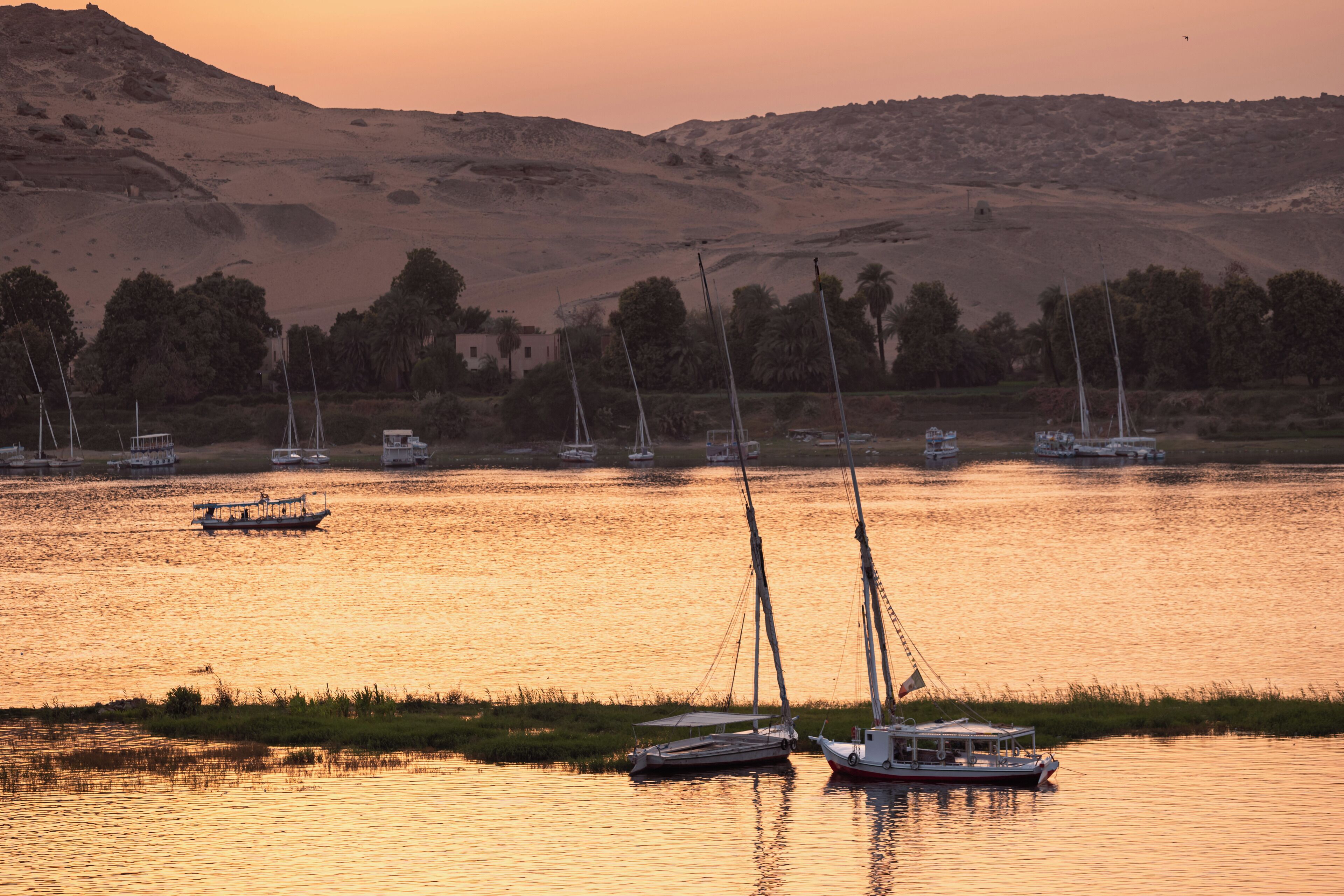 A calm river with boats and a distant hill.