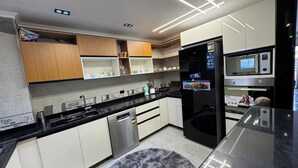 A modern kitchen with stainless steel appliances, wooden cabinets, and a black refrigerator with a digital display. - Relaxation (Aswan)