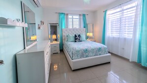 A bedroom with a large bed, a dresser, a vanity, and a mirror.