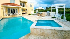 Un espace piscine comprenant deux piscines distinctes, un coin salon extérieur et une terrasse couverte.