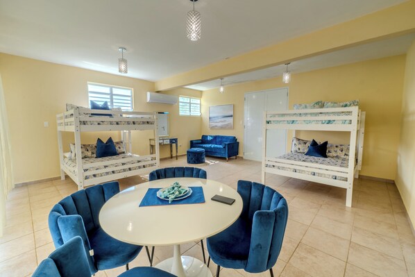 Een kamer met stapelbedden, een ronde tafel en blauwe stoelen.