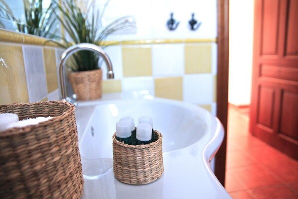 A bathroom with a white sink, a wicker basket, and a small container with bottles.