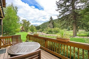 Une terrasse en bois avec une table ronde et des chaises, entourée d’une balustrade en bois.
