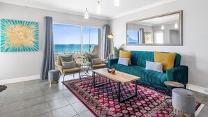 Un salon moderne avec un canapé de couleur turquoise, une table basse en bois et un tapis à motifs rouges.