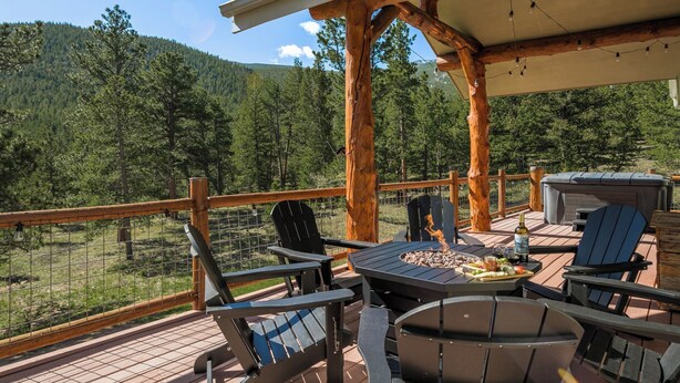 Een terras buiten met houten stoelen, een tafel, een barbecue en een jacuzzi.
